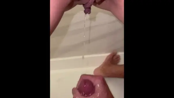 She pisses on his cock while he strokes it then starts fingering herself